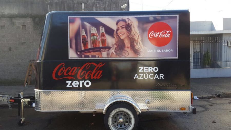 Trailer de OCHO ploteado de punta a punta con la gráfica de una marca de bebidas, con la lanza de remolque y la rueda jockey a la vista